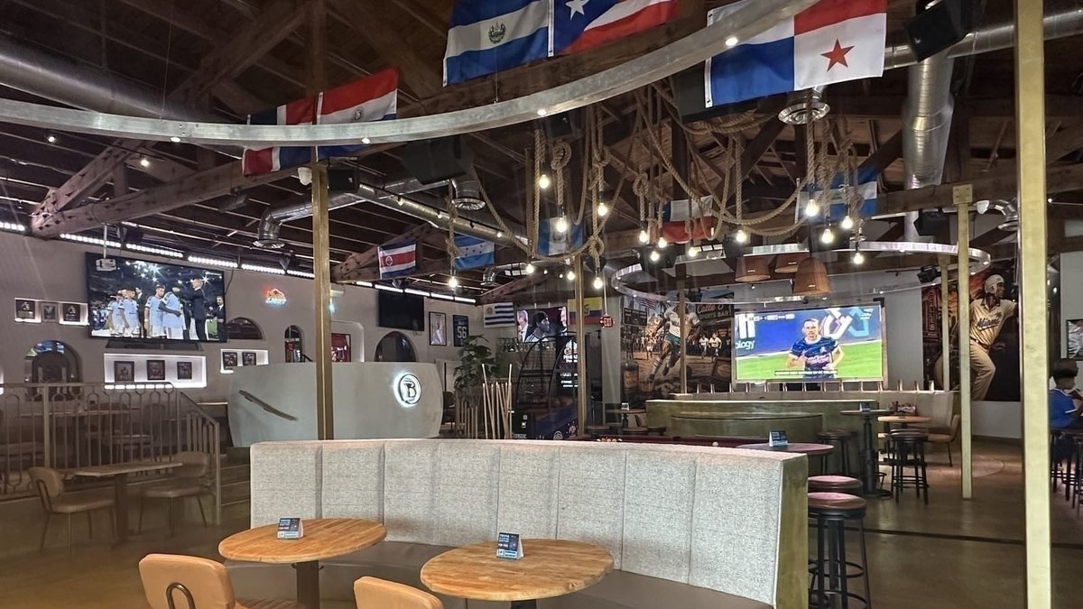 The TV wall, bar and neighborhood flags inside Calle 8 Sports Bar in Little Havana
