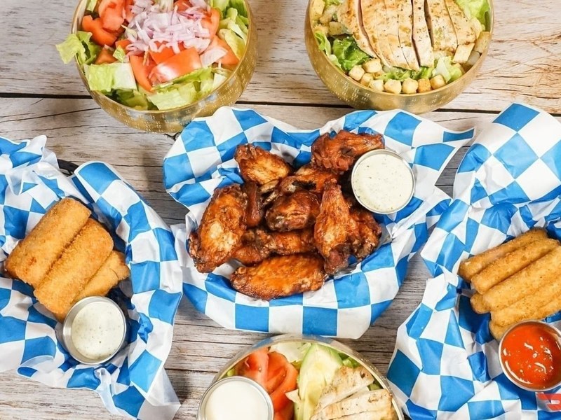 Magic City Wings, mozzarella sticks and salads on the table at Calle 8 Sports Bar